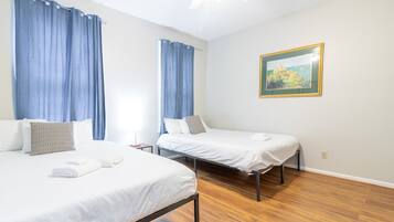 Une chambre d’hôtel avec deux lits simples, un tableau au mur et un plancher en bois.