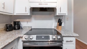 A kitchen with white cabinets, a stainless steel stove, a coffee maker, and a knife block. - Pet-Friendly Duplex Near Riverwalk w/ Free Parking (Columbus)