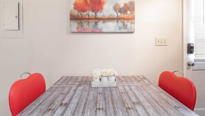 A dining area with a wooden table, two red chairs, and a painting of trees on the wall. - Pet-Friendly Duplex Near Riverwalk w/ Free Parking (Columbus)