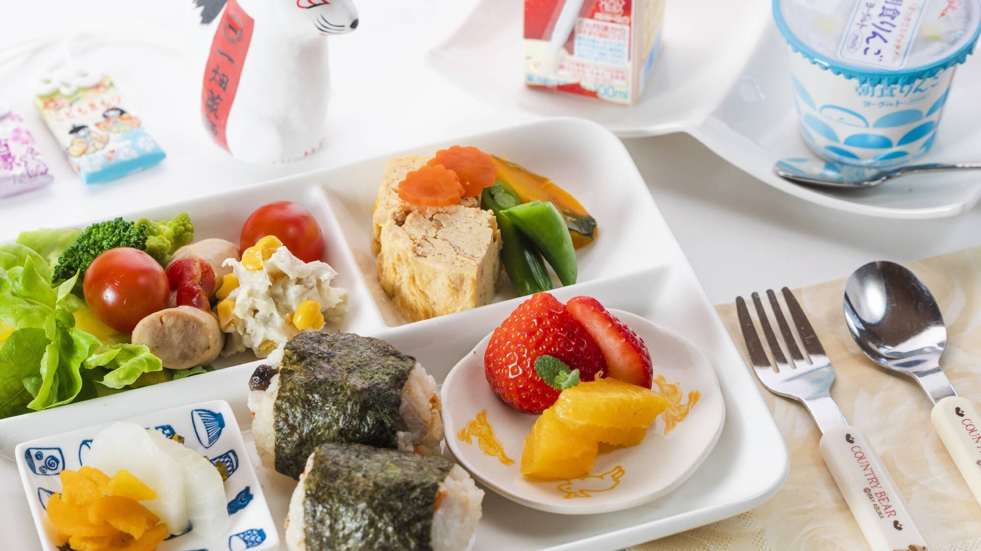 A meal with various dishes including sushi, vegetables, and a fruit plate.