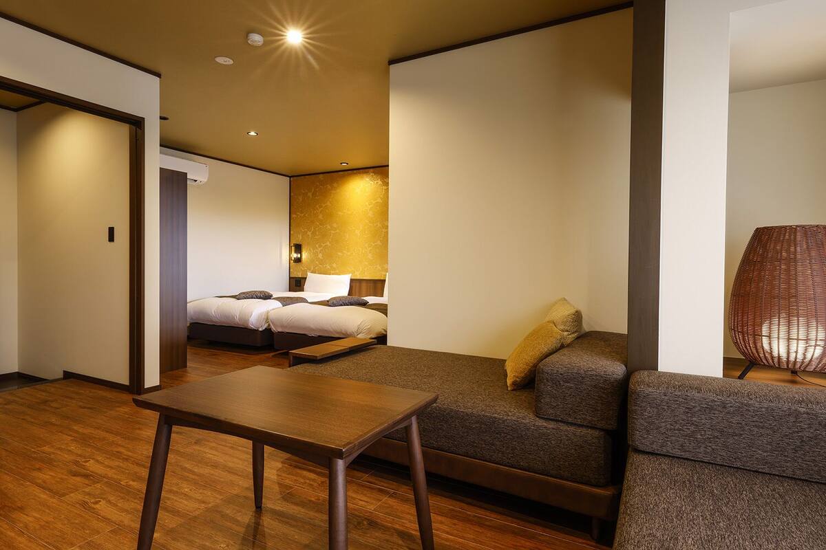 Una habitación de hotel con una cama, un sofá, una mesita y una lámpara.