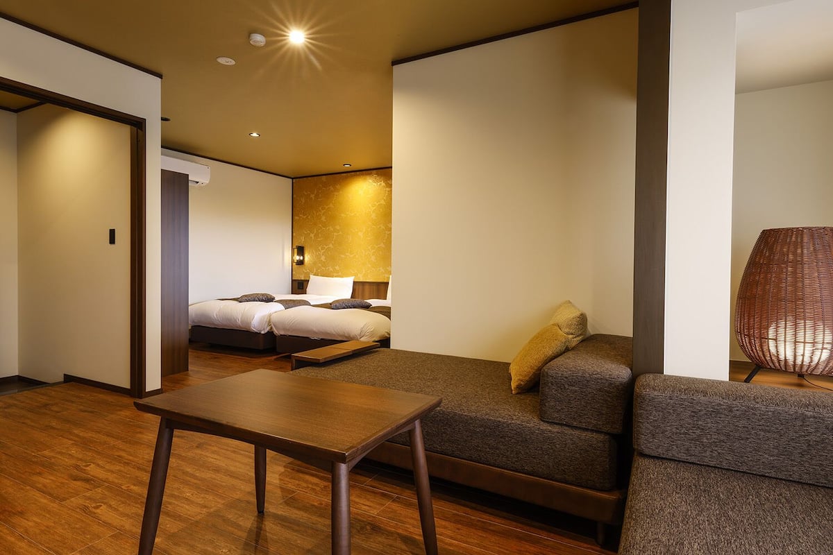 Una habitación de hotel con una cama, un sofá, una mesita y una lámpara.