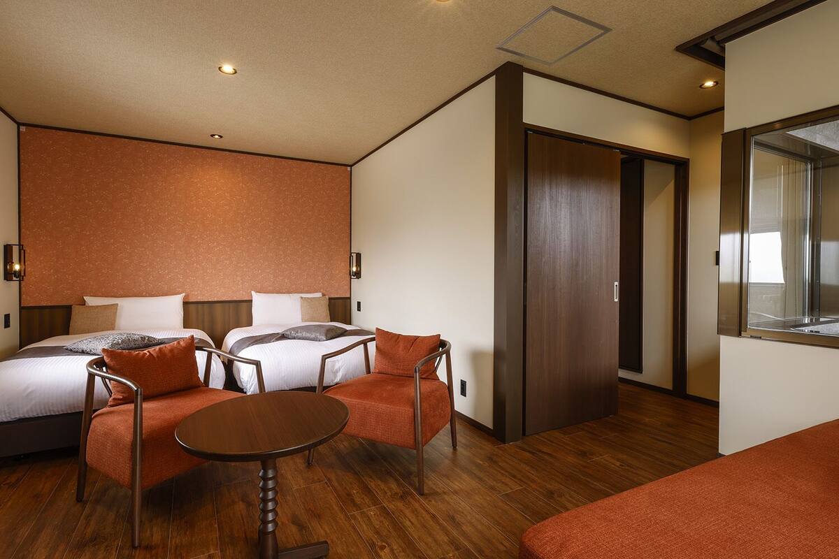 Una habitación de hotel con dos camas, una mesa de comedor y un armario.