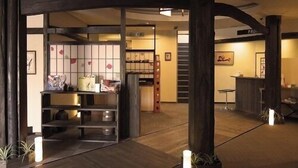 Tilava aula, jossa on korkea kattokorkeus, puiset kattopalkit ja vastaanottotiski.