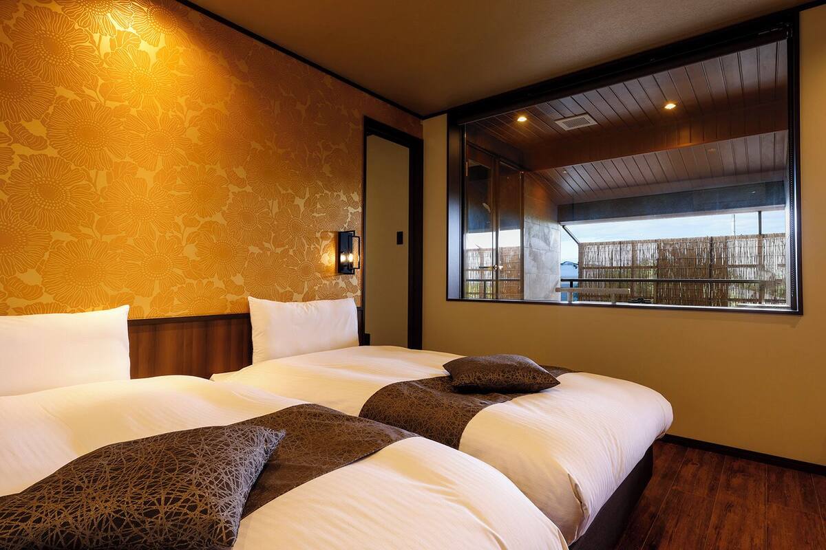 Una habitación de hotel con una cama grande, un ventanal con vistas y un papel tapiz estampado.