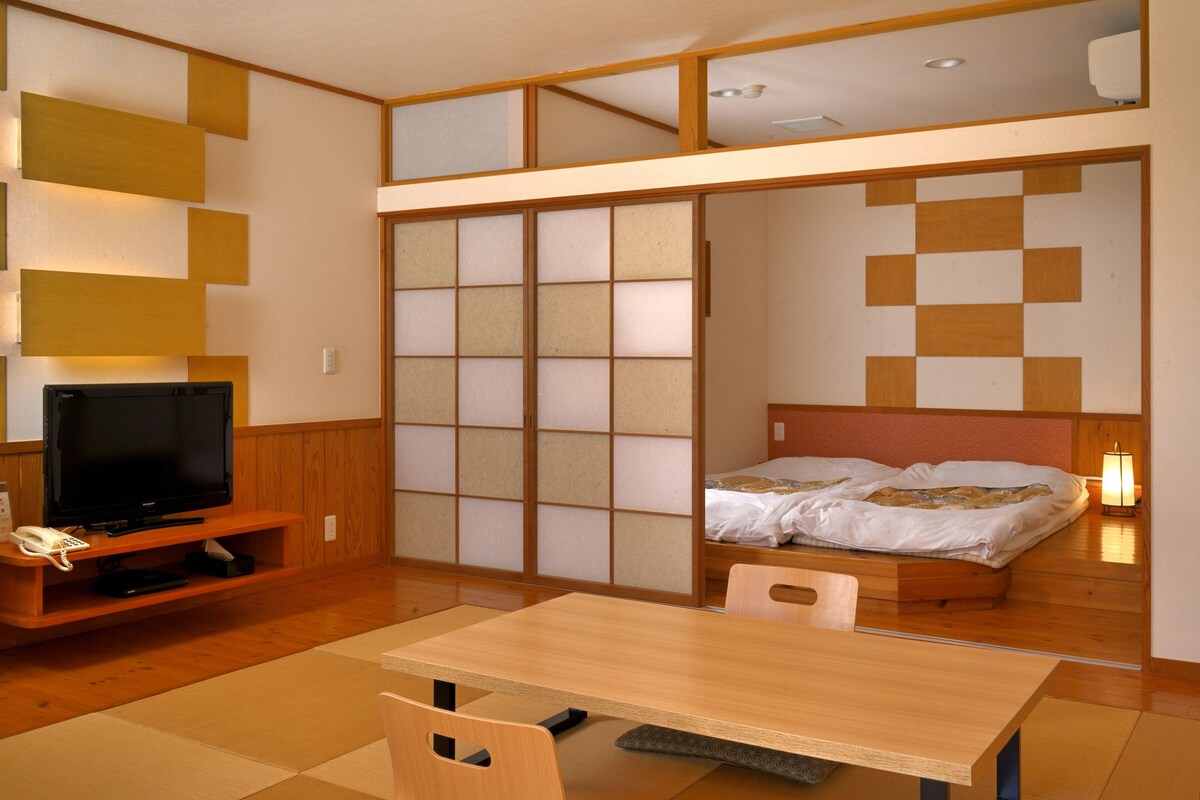 Ett hotellrum med en tv, en säng, ett bord och en stol.