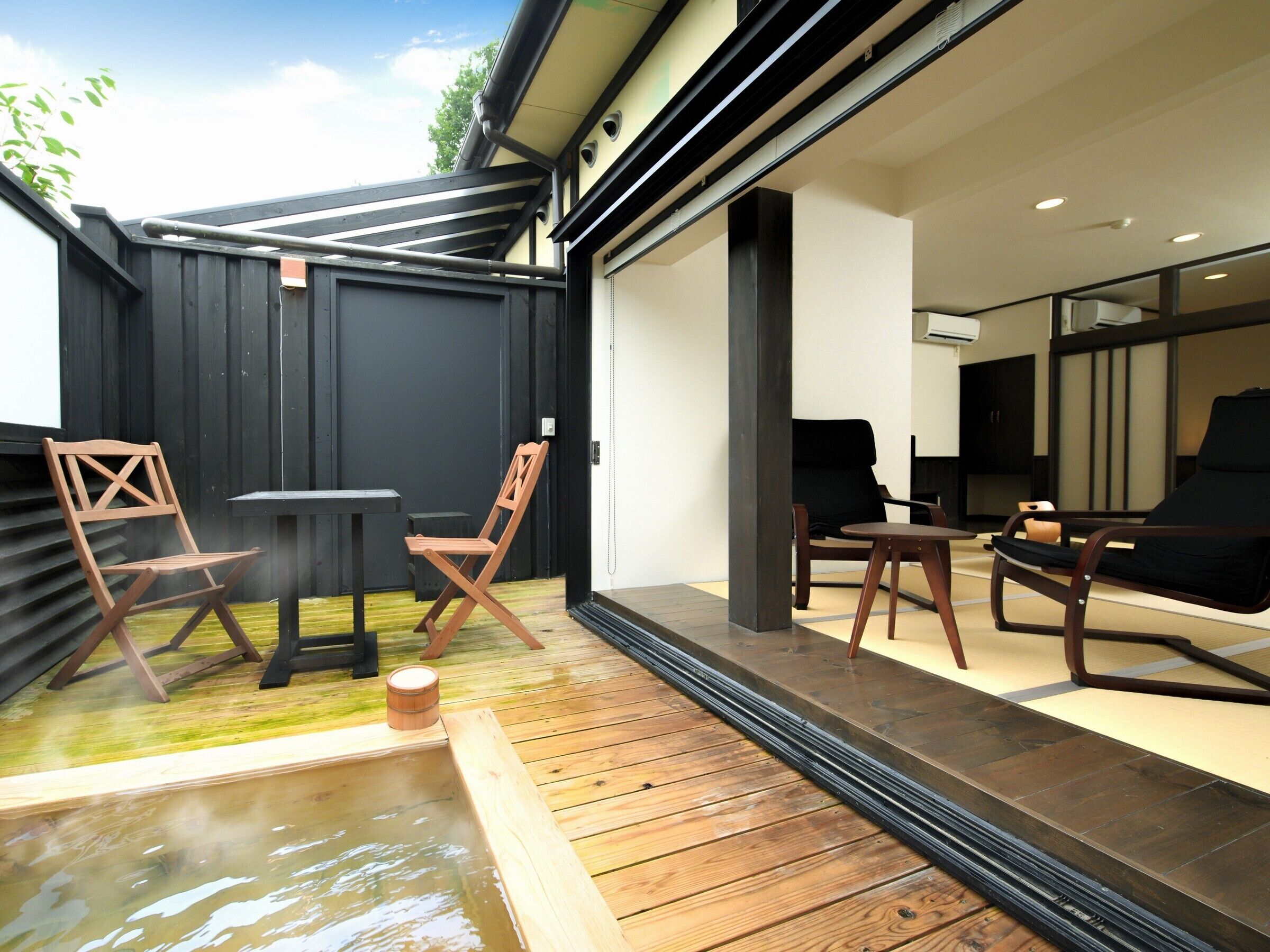 A modern outdoor space with a wooden deck, a hot tub, and seating arrangements.