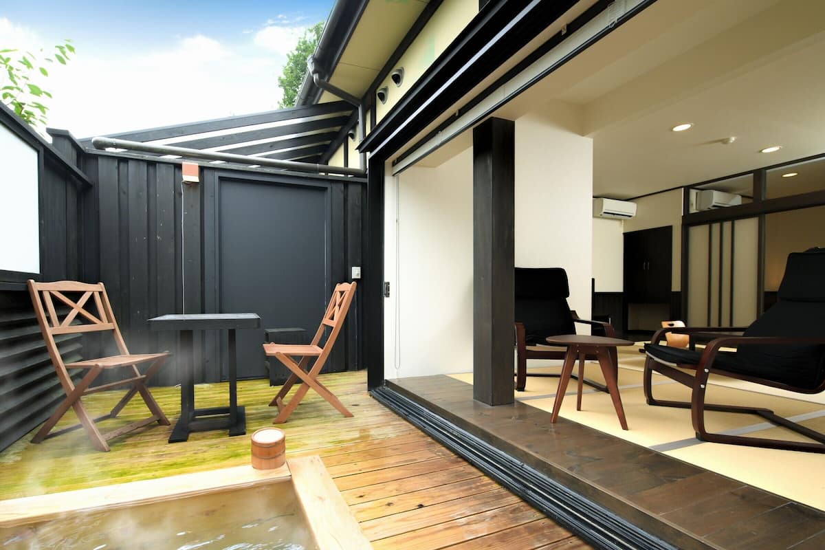 A modern outdoor space with a wooden deck, a hot tub, and seating arrangements.