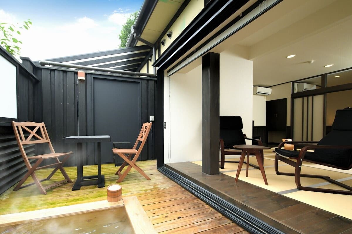 A modern outdoor seating area with wooden furniture and a small hot tub.