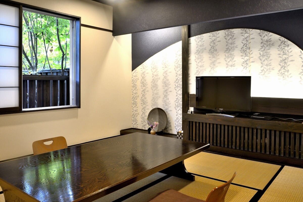A traditional Japanese-style room with tatami flooring, a low table, and a television.