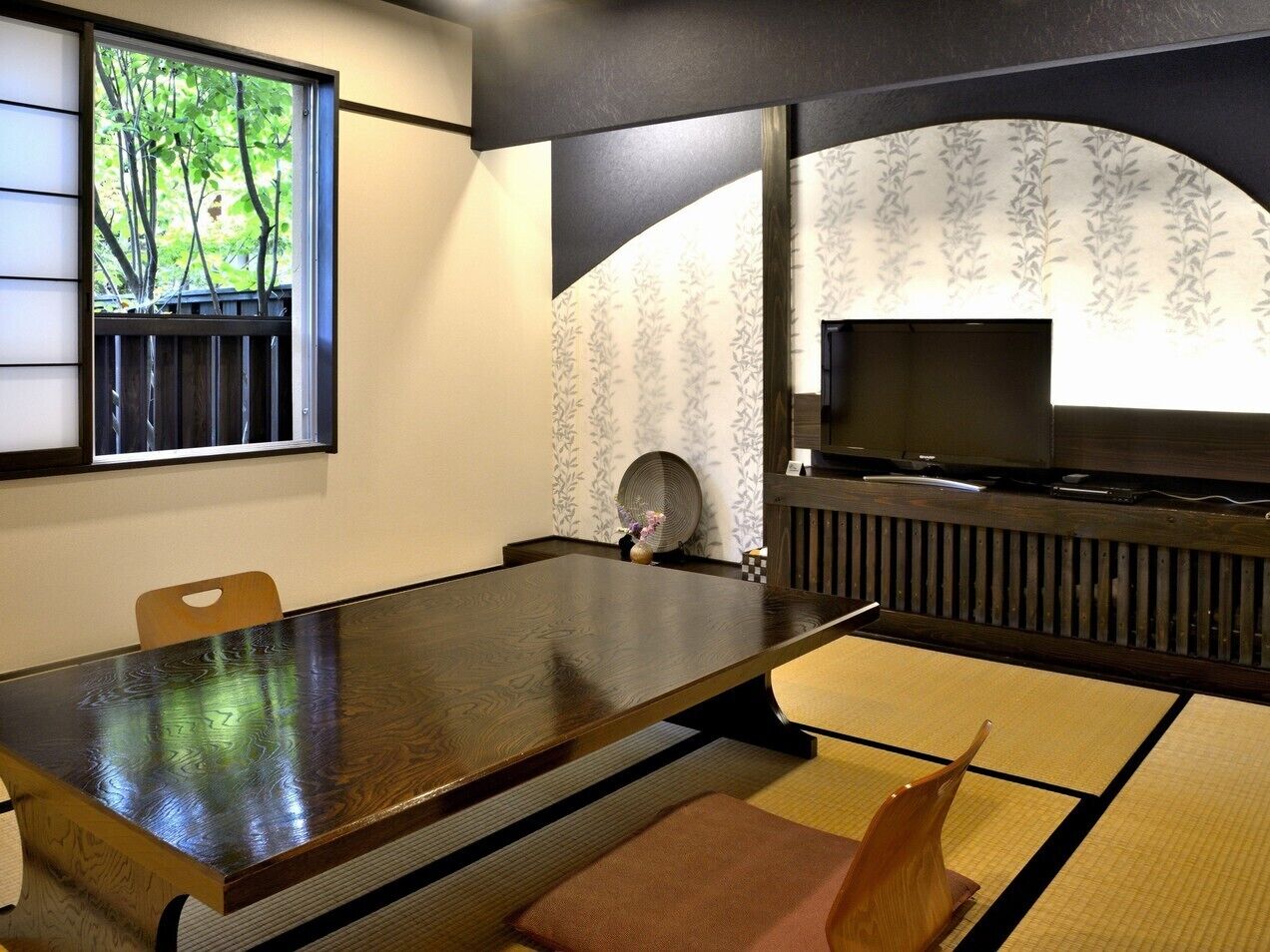 A traditional Japanese room with tatami flooring, a low table, and a television.