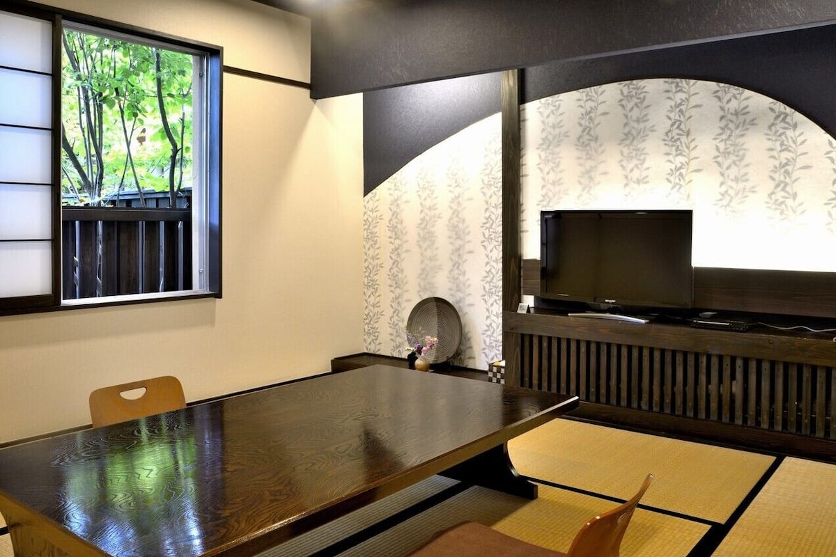 A traditional Japanese room with tatami flooring, a low table, and a television.