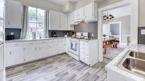 Een moderne keuken met witte kasten, een inbouwoven en een groot raam.
