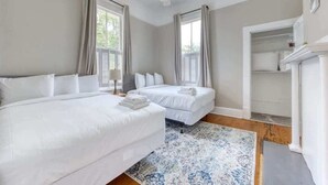 Een slaapkamer met twee bedden, een plafondventilator en een groot raam met gordijnen.