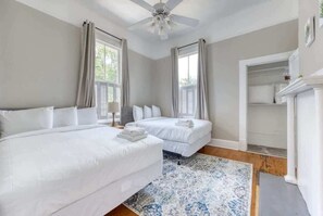 A bedroom with two beds, a ceiling fan, and a large window with curtains. - Near Parks Downtown & Riverwalk: Midtown Muse Sleeps 14 (Columbus)