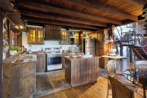 Une cuisine rustique avec des meubles de rangement en bois, un poêle et un réfrigérateur.