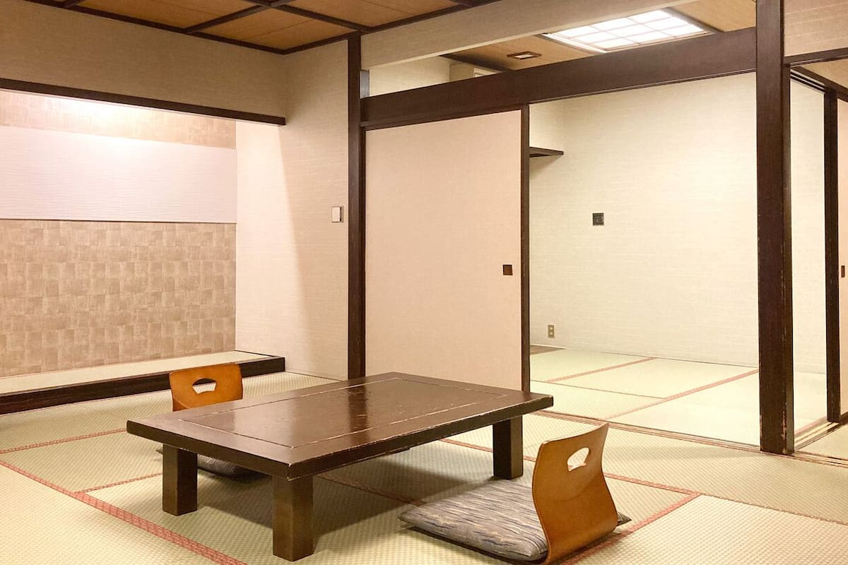 A traditional Japanese room with tatami flooring, a low wooden table, and sliding doors.