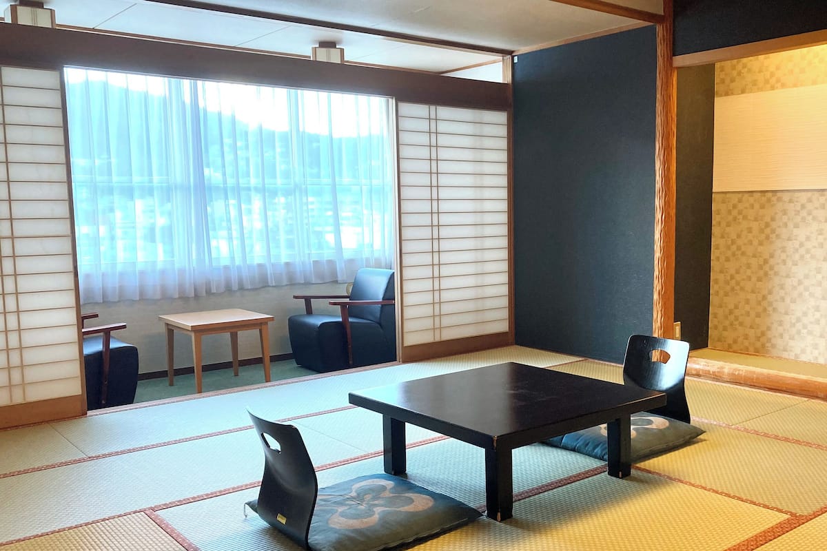 A traditional Japanese room with tatami flooring, a low table, a sofa, and a sliding door with shoji screens.