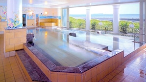 Una amplia piscina cubierta con vistas al mar, rodeada de paredes y columnas revestidas de azulejos.