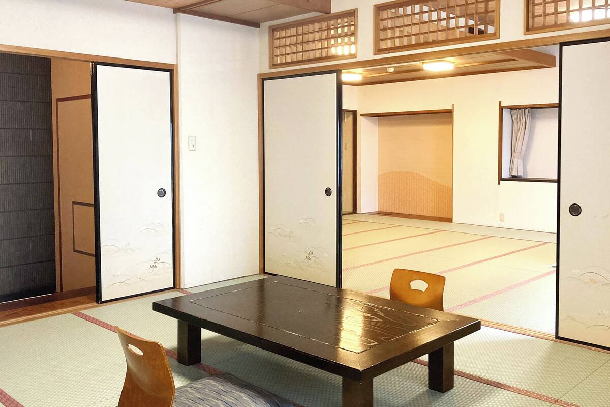 A traditional Japanese room with tatami flooring, a low wooden table, and sliding doors.