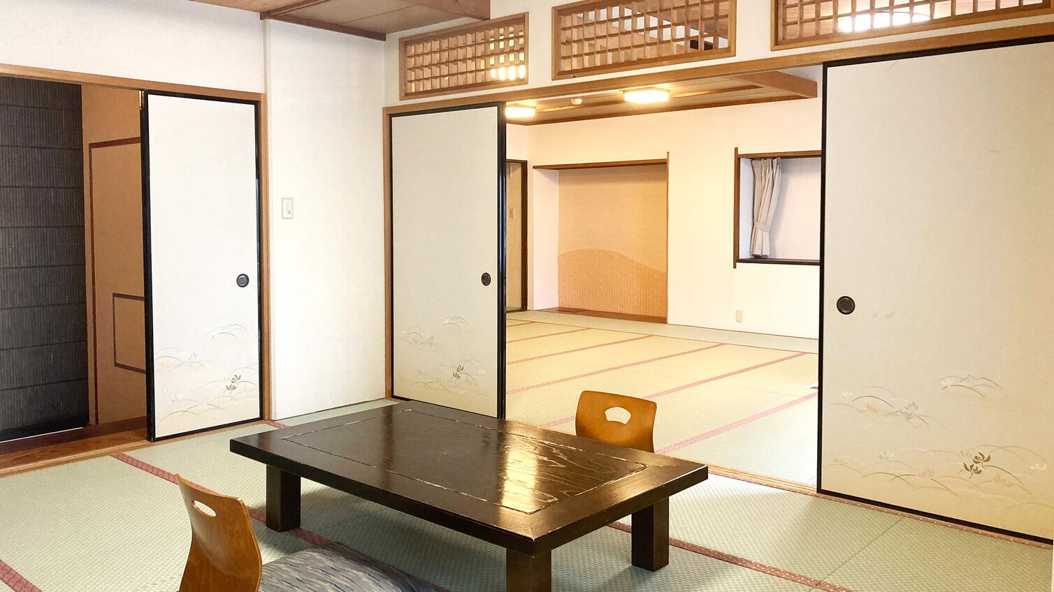A traditional Japanese room with tatami flooring, a low table, and sliding doors.