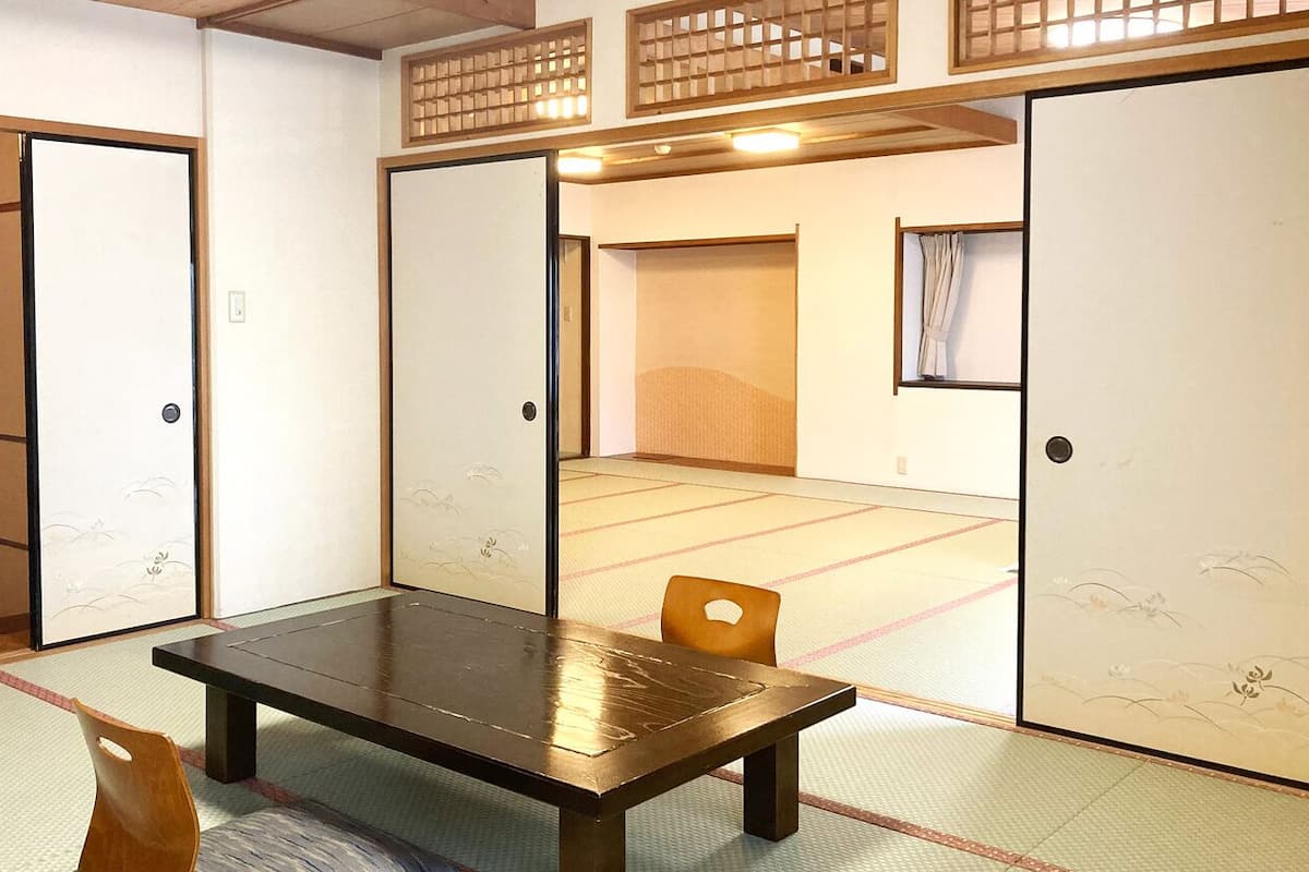 A traditional Japanese room with tatami flooring, a low table, and sliding doors.