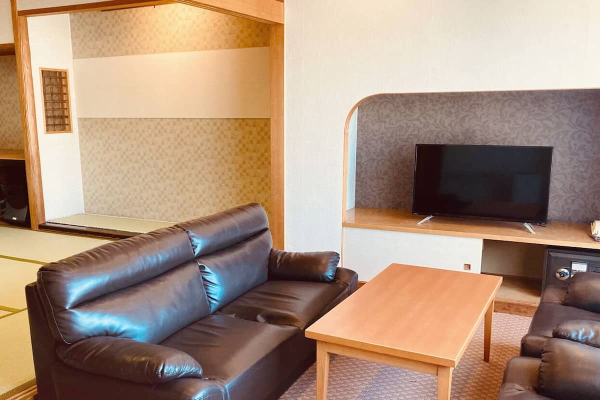 A compact living space with a sofa, a coffee table, a television, and a small kitchen area.