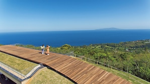 Una terraza de madera con vista al océano y una montaña distante.