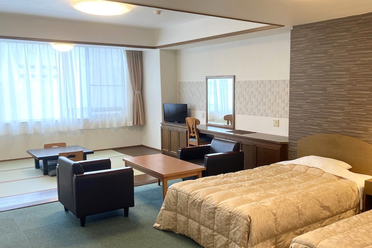 A hotel room with a bed, a desk, a chair, a television, and a window with curtains.