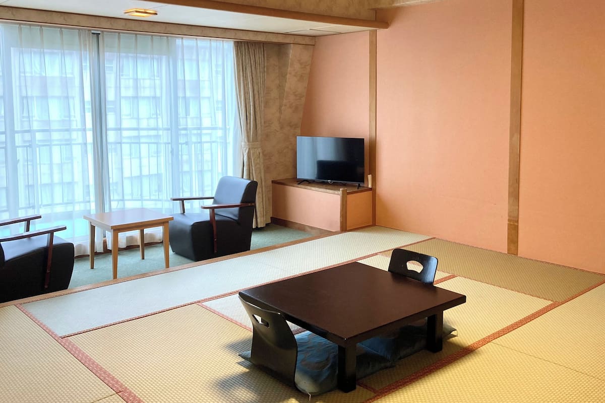 A hotel room with tatami mats, a television, a desk, and a chair.
