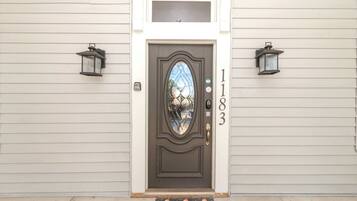 A front door with a glass panel, a numeric keypad, and two wall-mounted lanterns.