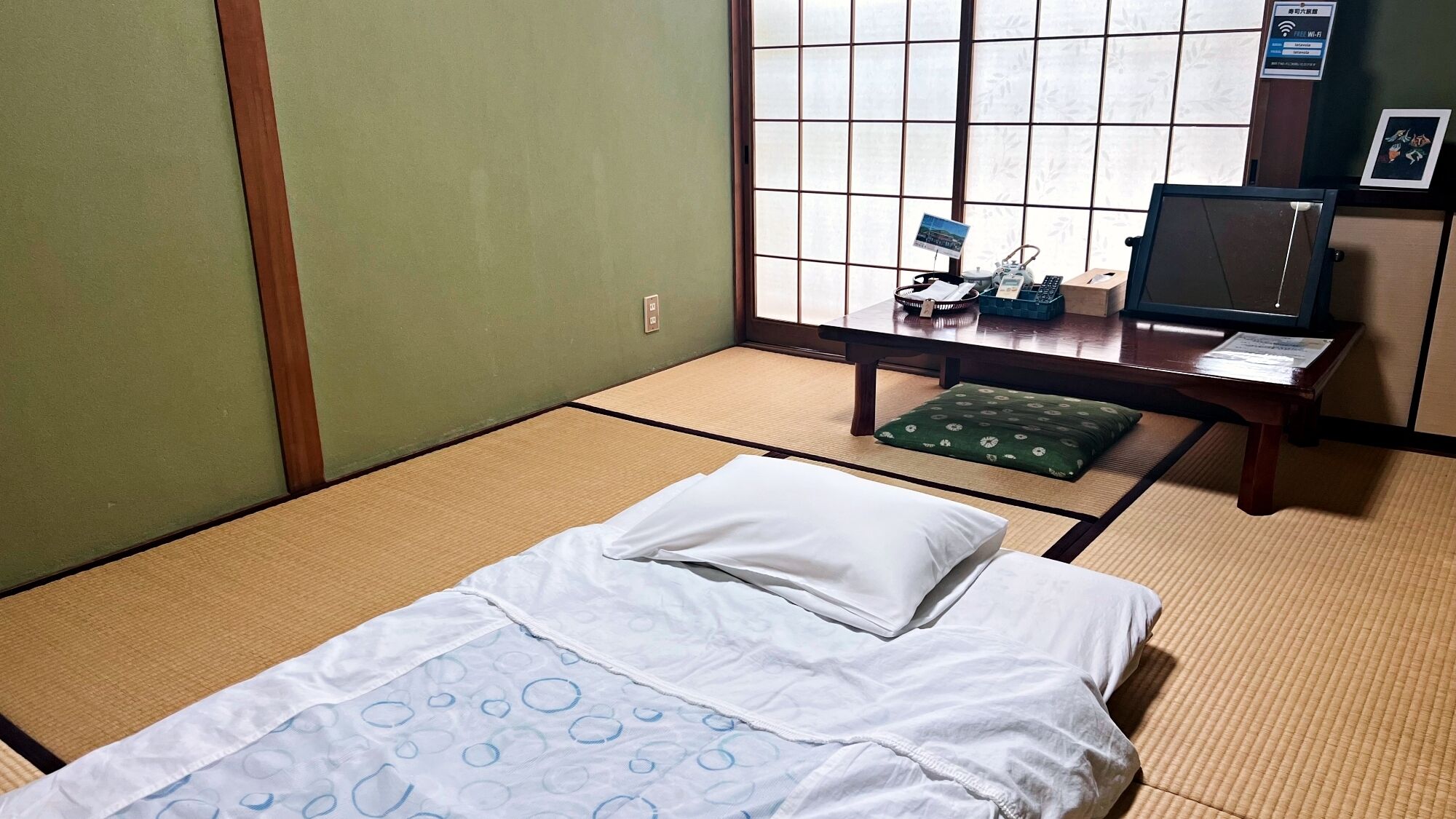 A tatami mat room with a bed, a desk, and a computer.