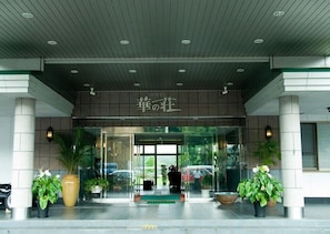 A hotel entrance with a sign in a foreign language, glass doors, and potted plants. - Hitoyoshi Onsen Hotel Hana no So (Hitoyoshi)