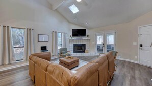 A spacious living room with a fireplace, leather sofas, and a flat-screen TV. - Near the Hospital and Dining - Sunrise Knoll Stay (Columbus)