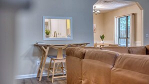 A modern living room with a sofa, a dining table, and a kitchen area visible through an open door. - Near the Hospital and Dining - Sunrise Knoll Stay (Columbus)