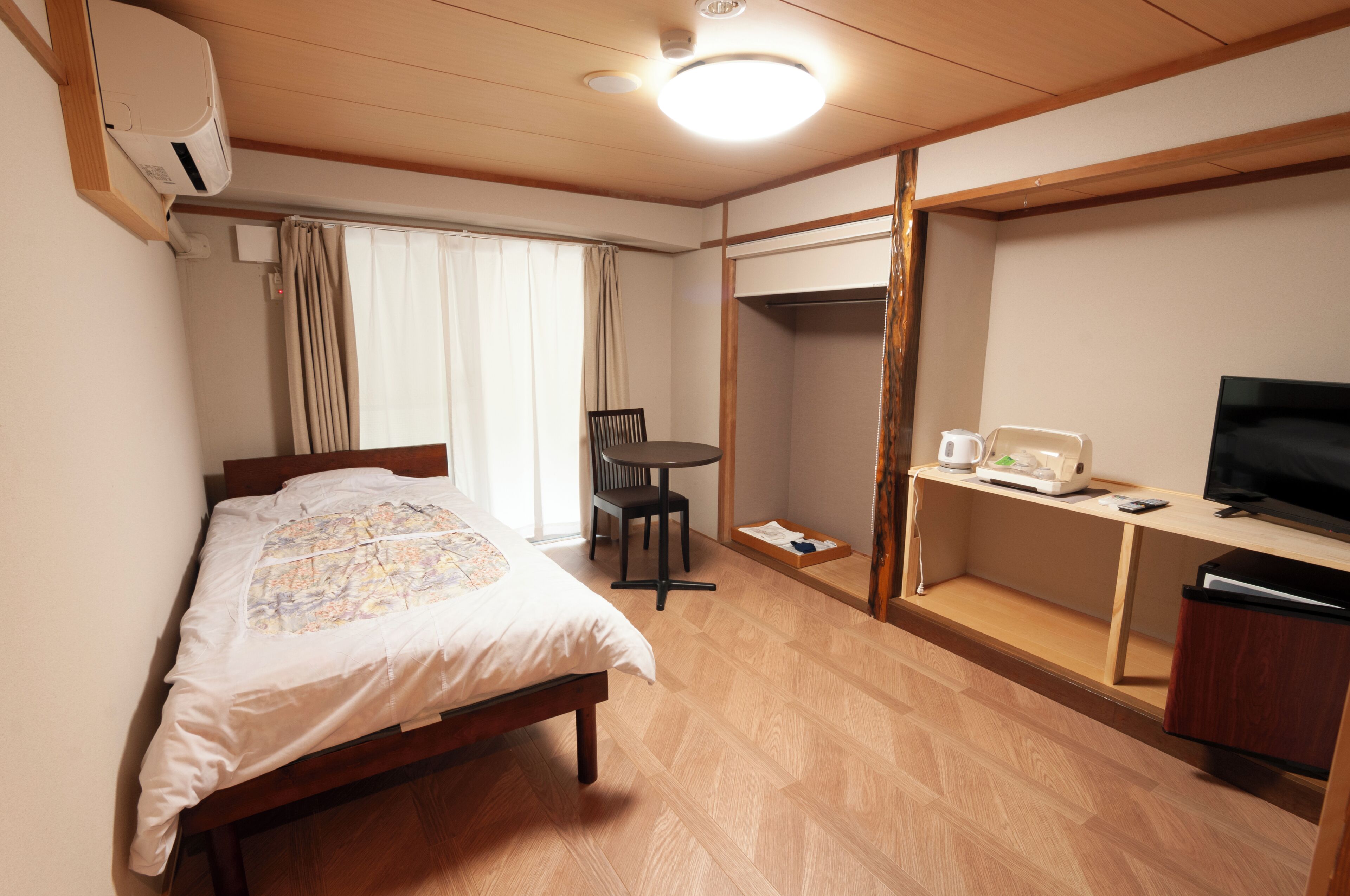 Ein Hotelzimmer mit Bett, Schreibtisch mit Fernseher, Sessel, Tisch und Kleiderschrank.