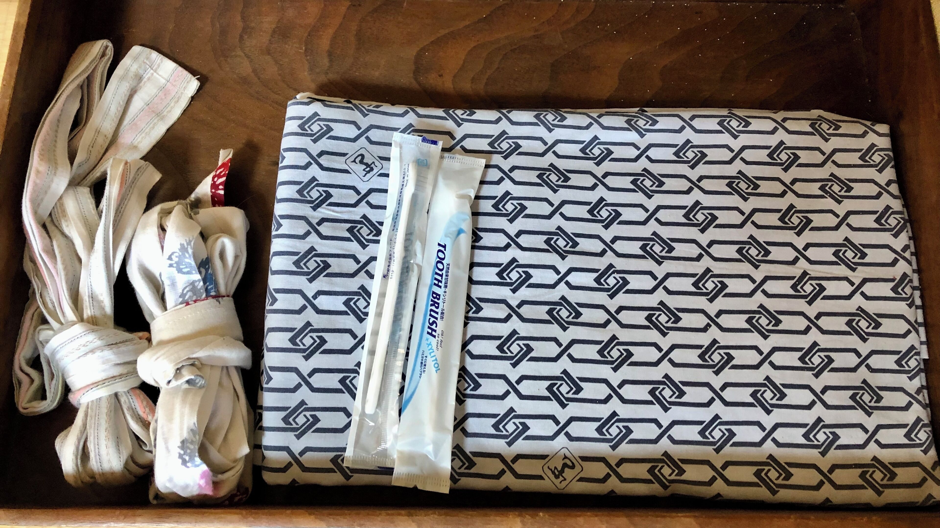 A wooden tray with a patterned cloth, a toothbrush, and a tube of toothpaste.
