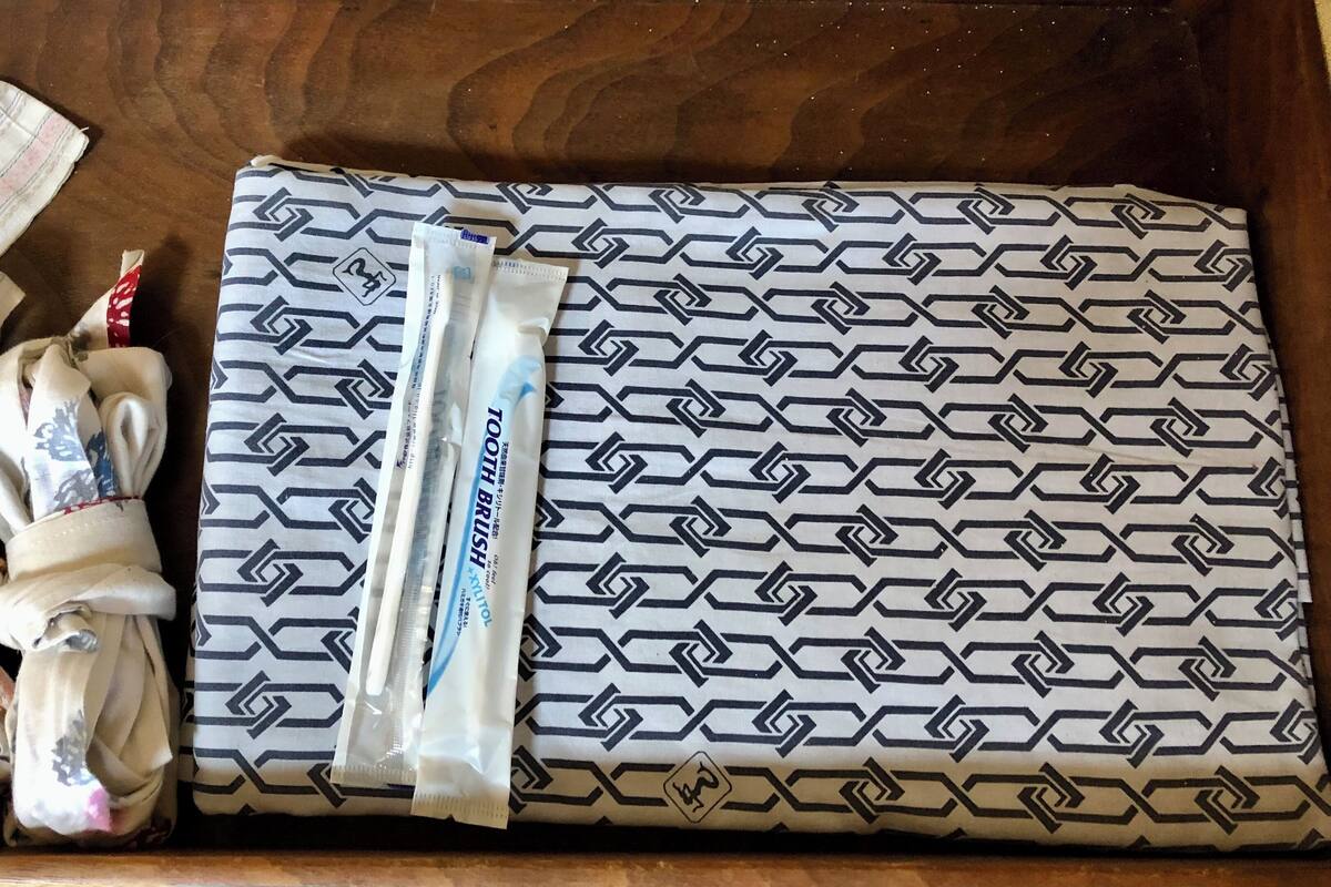 A wooden tray with a patterned cloth, a toothbrush, and a tube of toothpaste.