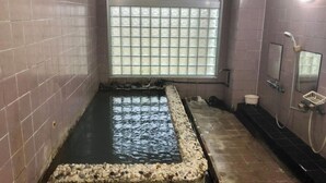 A small, enclosed pool with a pebble border, a window with a grid pattern, and a shower area with a hose. - Shirahama Onsen Minshuku Kotobuki (Shirahama)