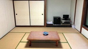A tatami mat room with a wooden table, a TV, and a wardrobe. - Shirahama Onsen Minshuku Kotobuki (Shirahama)