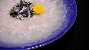 A bowl of clear soup with a flower garnish.