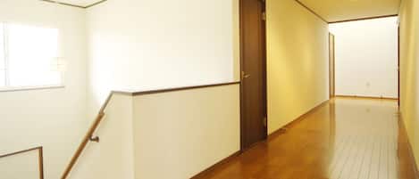 A hallway with wooden flooring, white walls, and a door.