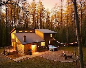 A cabin with a stone exterior, a metal roof, and a fire pit in the yard.
