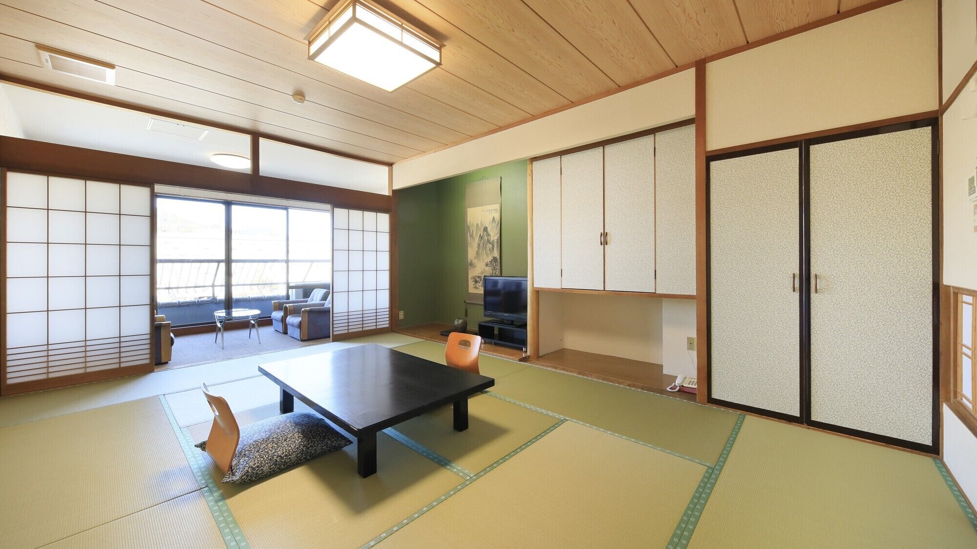 A traditional Japanese room with tatami flooring, a low table, a sofa, and sliding doors.