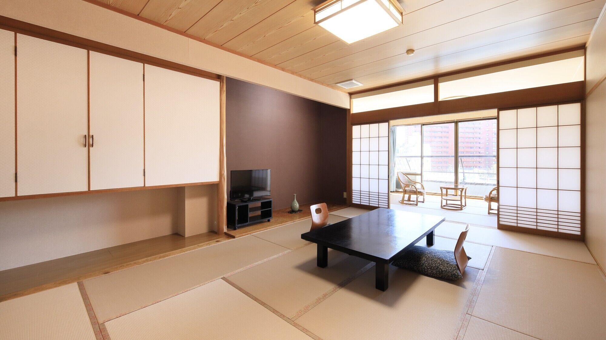 A traditional Japanese room with tatami flooring, a low table, a television, and sliding doors.