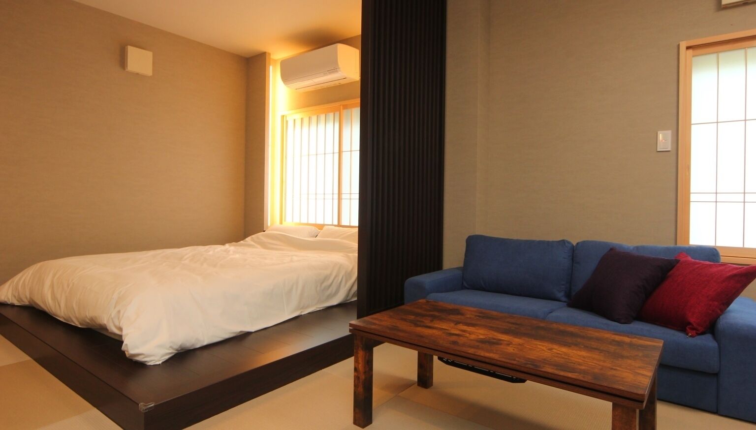 Ein Zimmer mit einem Bett, einem blauen Sofa und einem Holztisch.