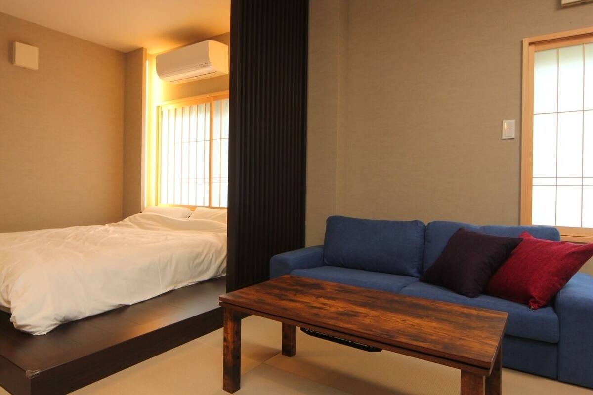 A room with a bed, a blue sofa, and a wooden table.