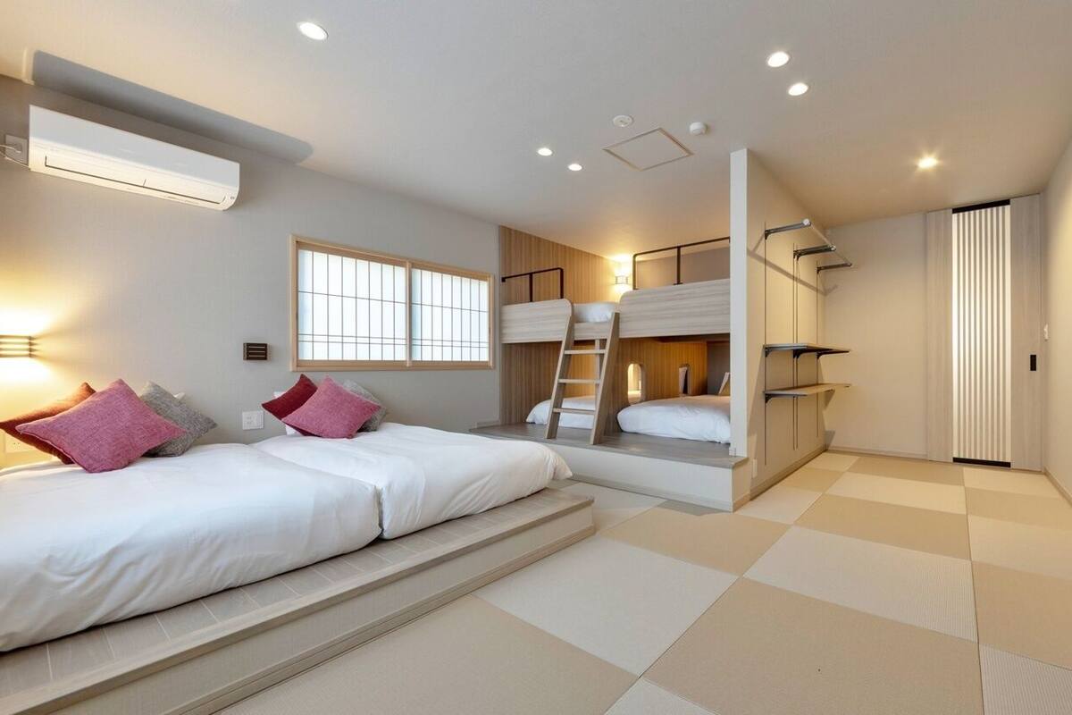 A hotel room with a bed, a window, a built-in ladder, and a sliding door.