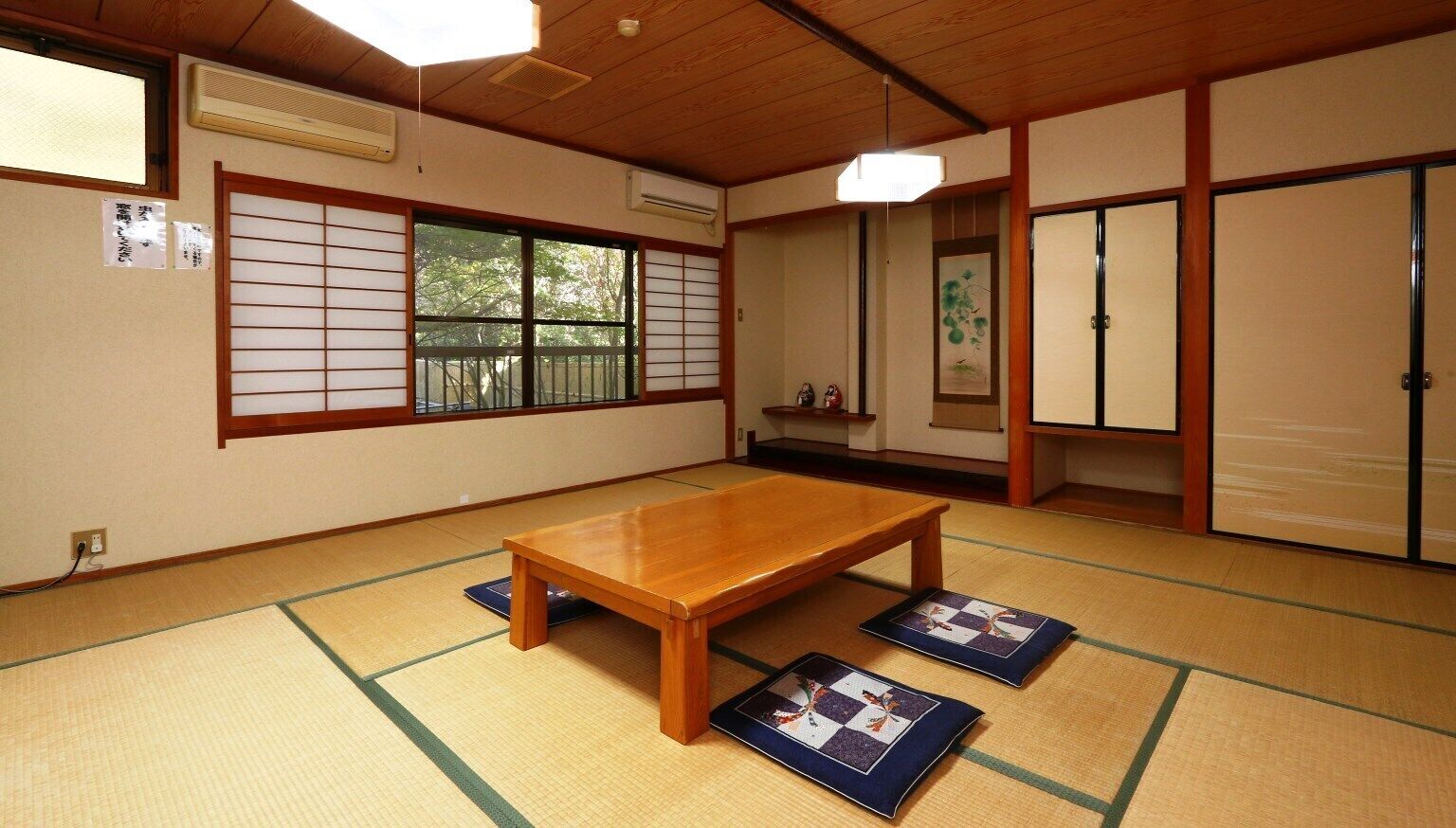 Ein traditioneller japanischer Raum mit Tatami-Böden, einem Holztisch, Schiebetüren und Blick durch einen Shoji-Bildschirm.