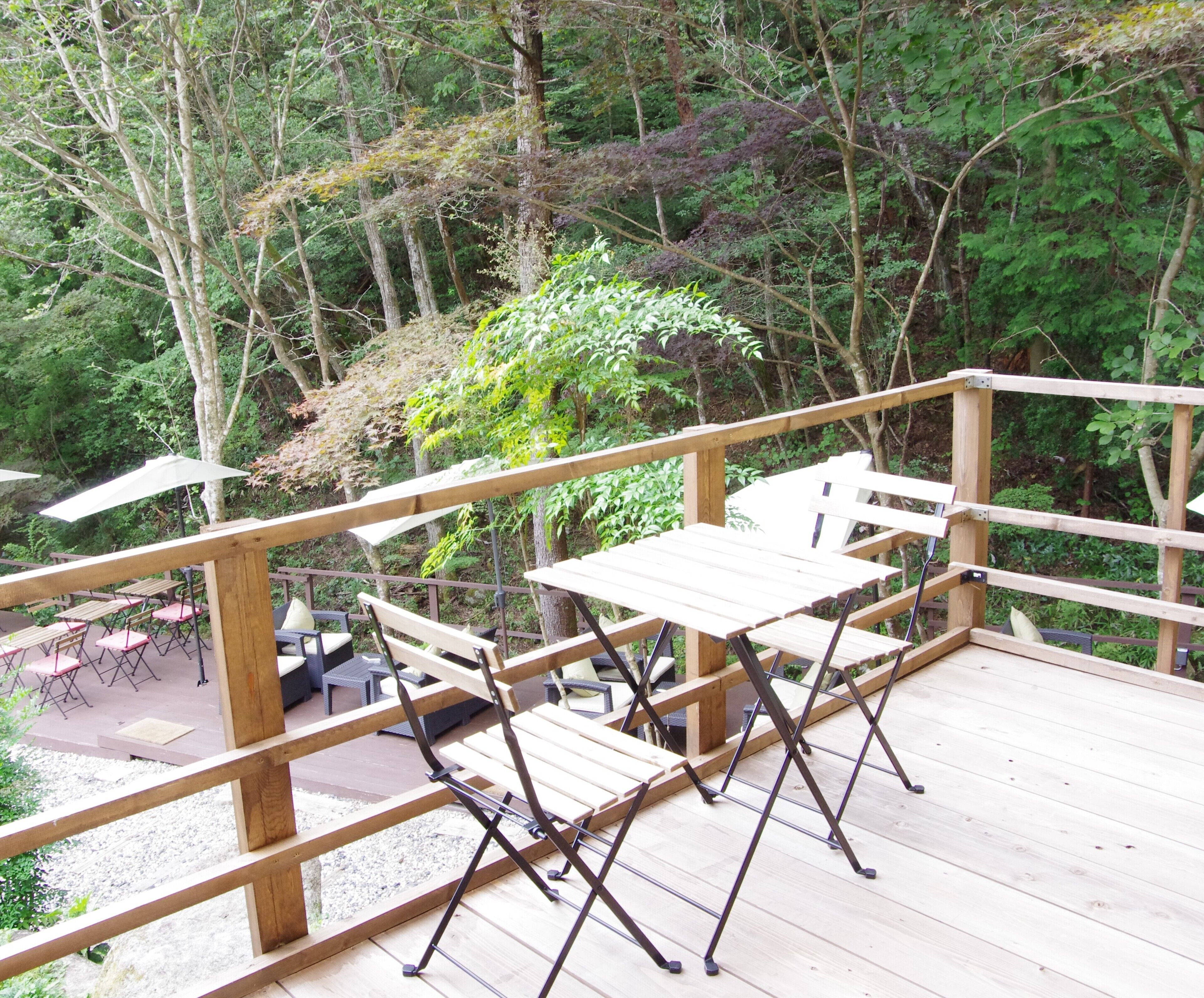 Eine Holzterrasse mit Tischen und Stühlen, umgeben von dichtem Wald.